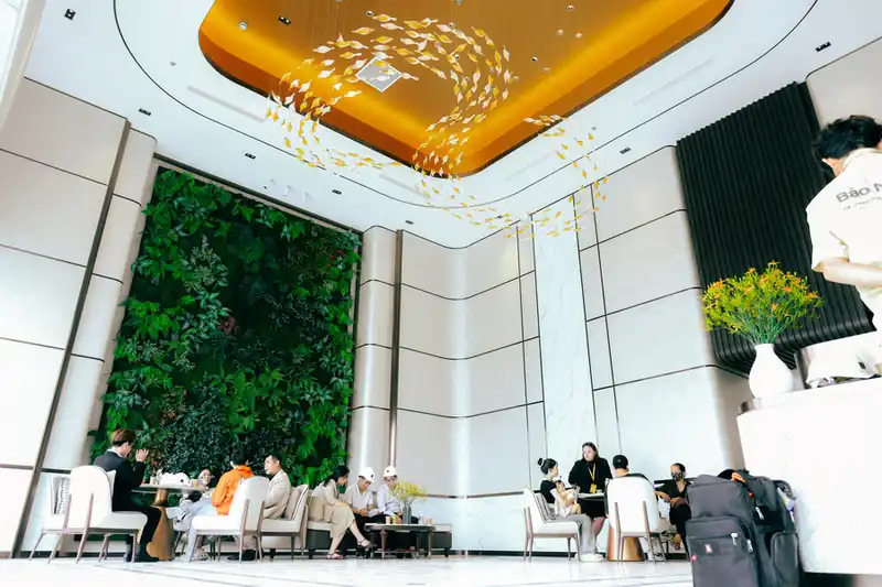 Ảnh thực tế sảnh Green Skyline đã hoàn thiện: tường cây xanh, trần đèn nghệ thuật và khu tiếp khách, tháng 06/2026