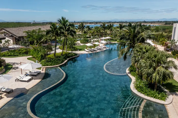 Hồ bơi giữa vườn nhiệt đới của Hoiana Resort & Golf, nơi có 3 hồ bơi, 1 hồ bơi vô cực và 8 sân pickleball