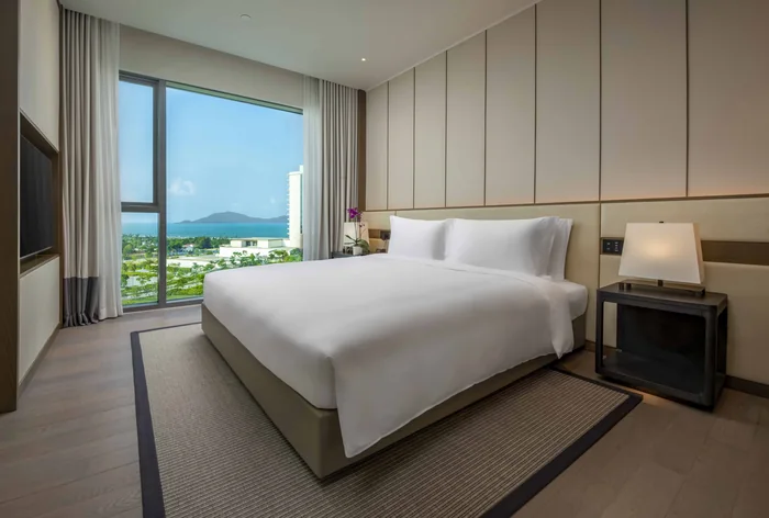 Phòng ngủ chính căn hộ Hoiana Residences, cửa kính lớn nhìn ra biển và rừng dương
