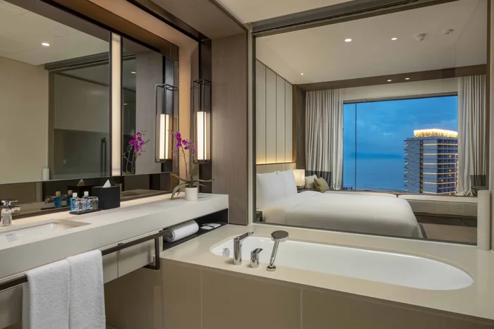 Phòng tắm có bồn tắm nằm cạnh cửa kính trong căn hộ Hoiana Residences