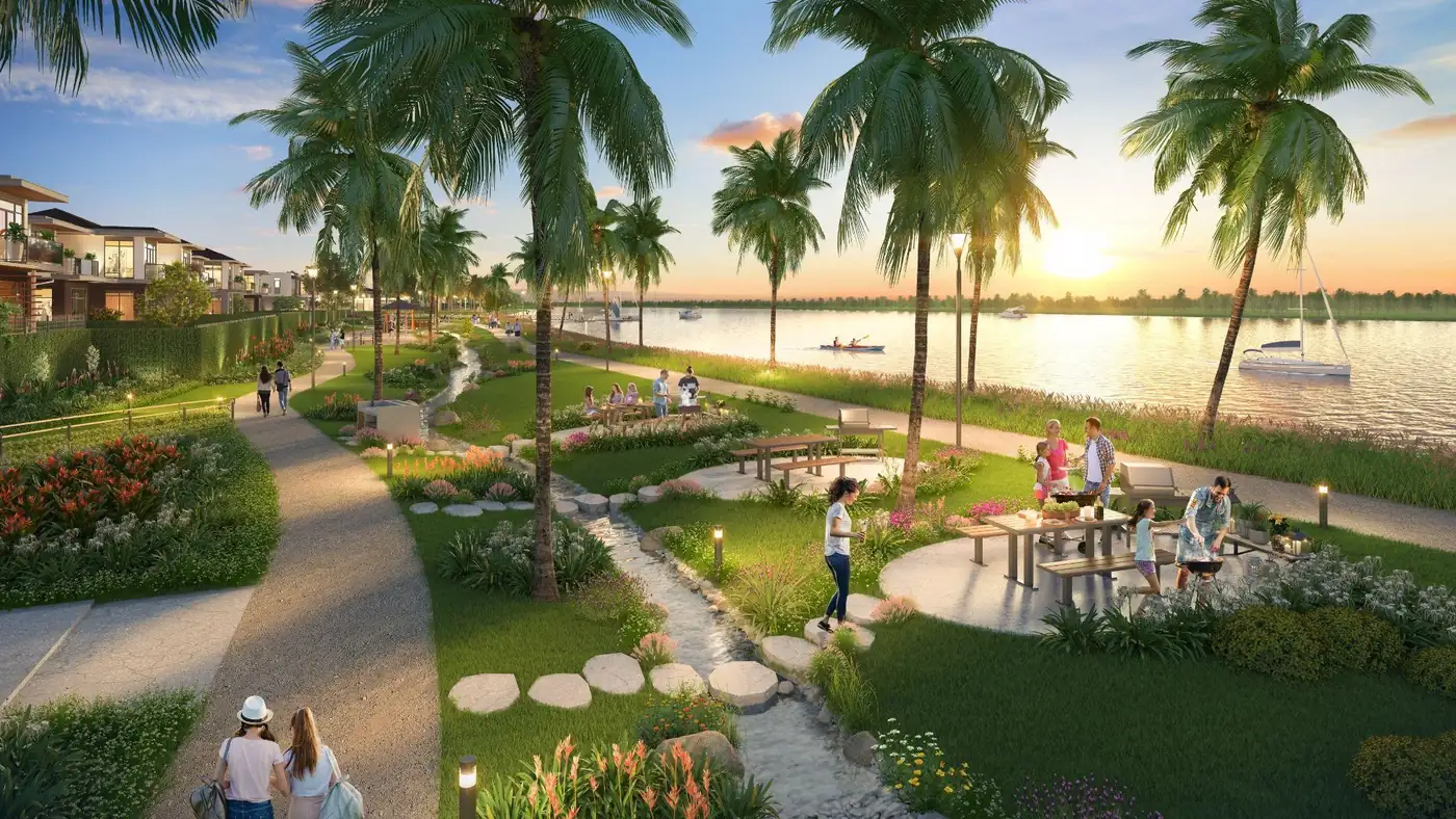 Phối cảnh cafe ngoài trời, bàn BBQ và lối dạo ven sông của The Aqua lúc hoàng hôn