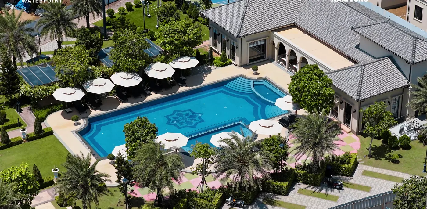 Club House Waterpoint với hồ bơi lát hoa văn, dù nghỉ và hàng cọ